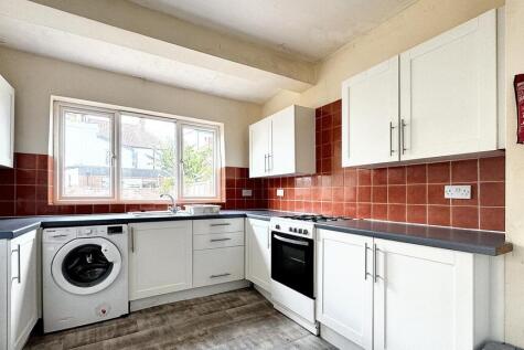 Bright, modern kitchen with white cabinetry, in...