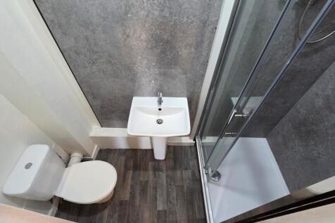 Compact modern bathroom with a corner shower en...