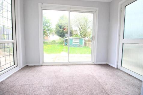 Bright sunroom with garden views and soft carpe...