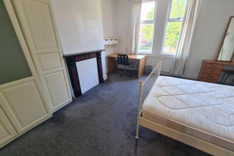 A bright, tidy bedroom featuring large windows ...