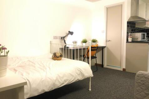 A bright, cozy single bedroom featuring a neat ...