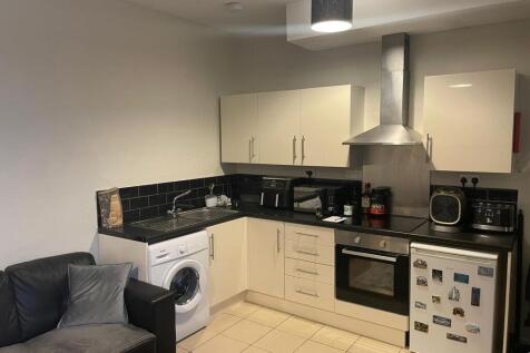 Modern open-plan kitchenette with cream cabinet...