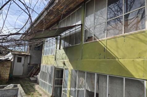 Side of a building featuring green painted panels and large windows, with an entrance door and yard area.