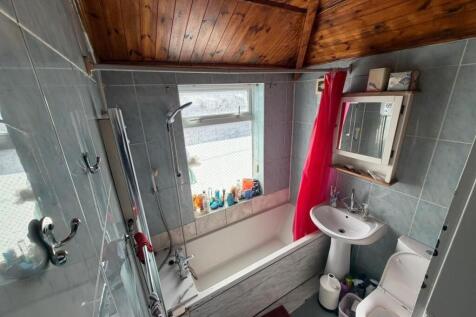 Bright bathroom with bath and wood panel ceilin...