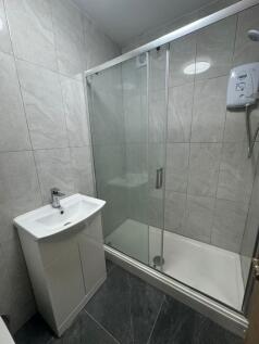 Modern tiled bathroom with a glass-enclosed sho...