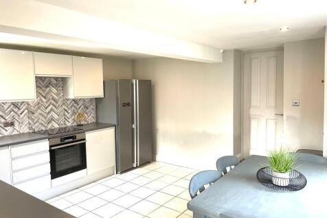 Modern kitchen featuring sleek white cabinetry,...