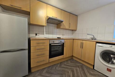 A modern kitchen featuring light wood cabinetry...