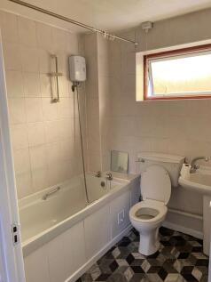 A clean and well-lit bathroom featuring a bath,...