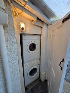 Compact utility cupboard with stacked washer dr...