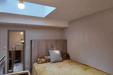 Cozy bedroom with a warm-toned bed, stylish hea...