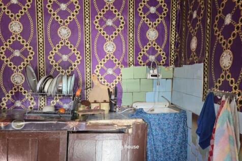Compact kitchen space showing a sink, tiled backsplash in green and blue, dish rack with plates, and kitchen utensils.
