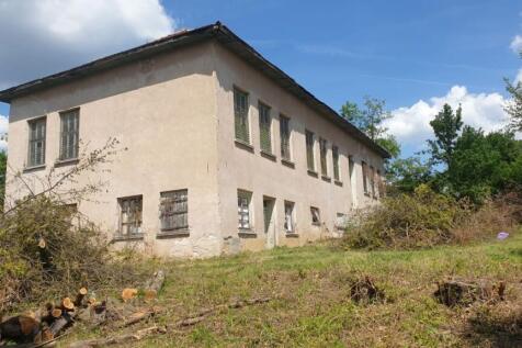 Side perspective of the old school building with barred windows and trimmed vegetation in the yard