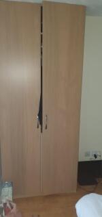 A simple wooden double-door wardrobe in a tidy ...