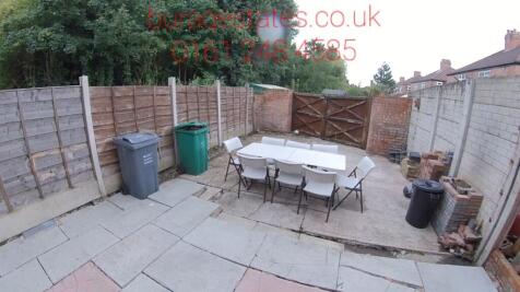 Paved rear garden with a central outdoor dining...