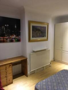 Neat furnished bedroom with warm wood flooring,...