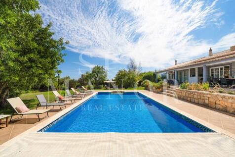 Private pool and main residence of a renovated Algarvian Quinta in Lagoa. Swimming pool surrounded by landscaped gardens and sun loungers.