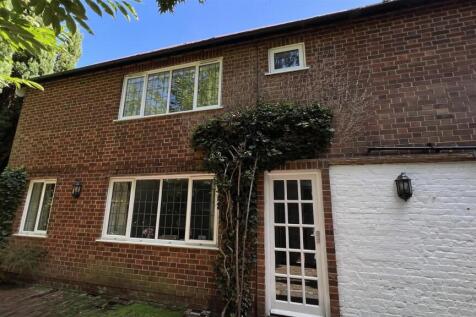 Brick-front house with driveway and mature tree...
