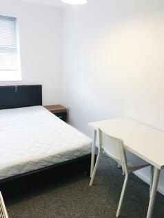 Bright, simply furnished bedroom with a double ...