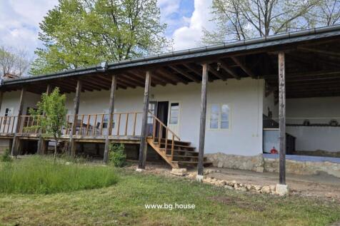 Exterior view of the house showing a long wooden veranda with steps leading to the garden area