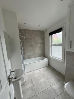Bright, modern bathroom with a tiled bath and m...