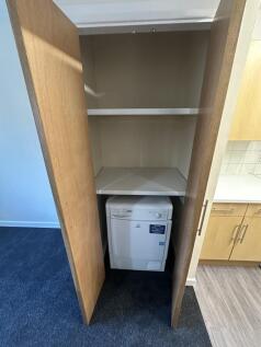 A tidy small storage area featuring a washing m...