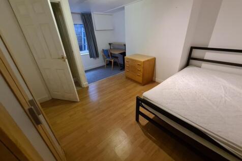 A tidy double bedroom featuring a bed, wooden f...