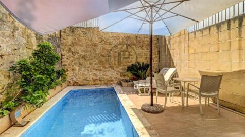 A small, private outdoor pool area with a stone wa
