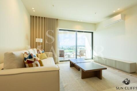 Sophisticated living room at Sun Cliffs Resort in Lagos, featuring elegant sofas, AC, and large glass door with ocean view.