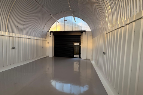 An empty arch with white lining and full height glazing to the front.