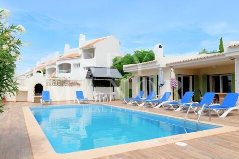 Private pool terrace of a 4-bedroom villa for sale in Carvoeiro, featuring sun loungers, outdoor dining, and a built-in barbecue area. Ideal Algarve holiday retreat.
