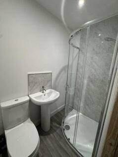 A modern bathroom featuring a curved glass show...