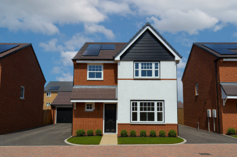 A modern two-story house with white and brick facade and solar panels on the roof stands on a paved