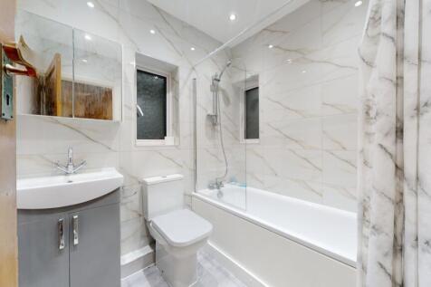Bright, modern bathroom with a bathtub and over...