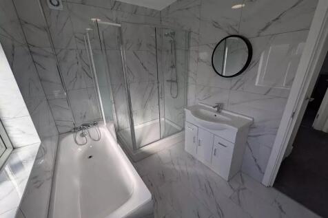 Elegant marble-effect suite with bath and showe...