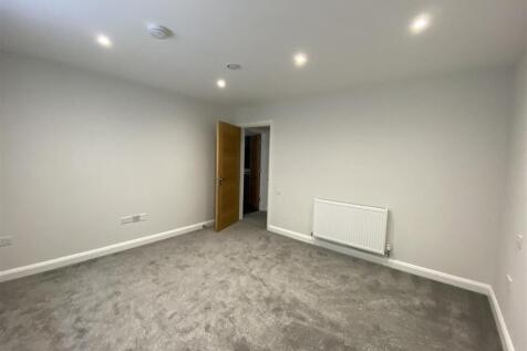 Spacious modern bedroom with plush grey carpet...