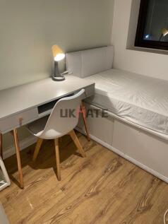 A cozy single bedroom featuring a simple bed, a...