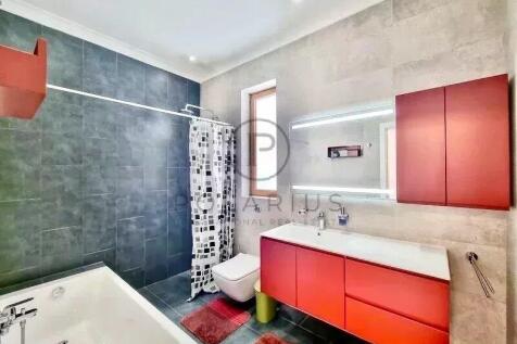 Modern bathroom with red vanity, black tiled showe