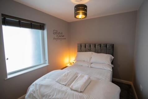 Cozy double bedroom with a plush upholstered he...