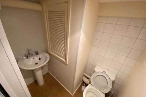 Compact bathroom with pedestal sink, tiled wall...