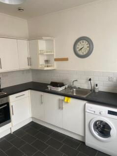 Modern kitchen with white cabinetry, black coun...