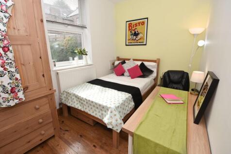 Bright, neatly furnished bedroom with a cosy si...