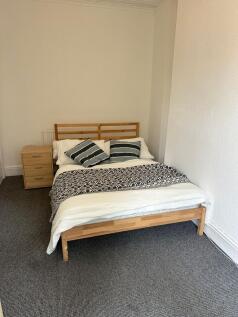 A cozy double bedroom featuring a wooden bed fr...