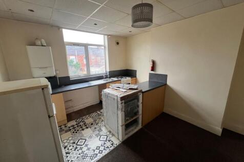 A compact kitchen space with patterned tiled fl...