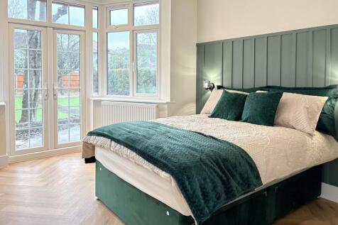 Bright, stylish bedroom with large bay windows,...