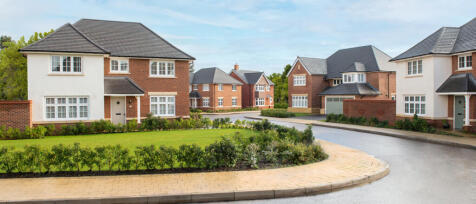 Modern residential housing estate with well-maintained gardens and paved roads under a partly cloudy