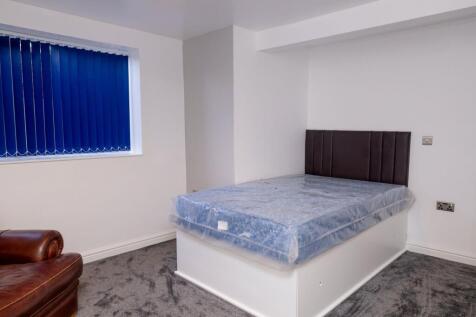 A simple and clean student bedroom with a bed w...