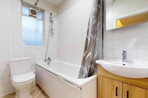 Bright, tiled bathroom with a bathtub and overh...