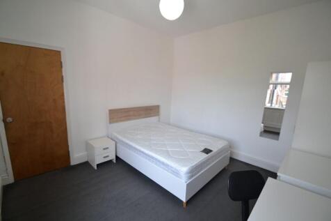 A clean, bright bedroom featuring a single bed ...