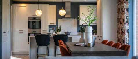 Modern open-plan kitchen and dining area with white cabinetry, black chairs, orange dining chairs, a