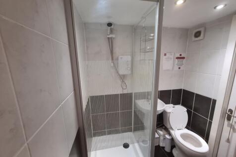 A modern bathroom suite featuring a glass-enclo...